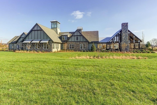 rear view of property with a standing seam roof, a chimney, metal roof, and a lawn