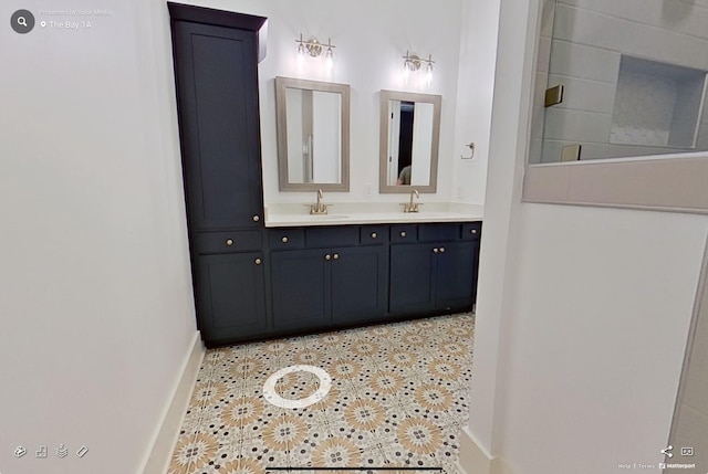 bathroom with double vanity, baseboards, a sink, and tile patterned floors