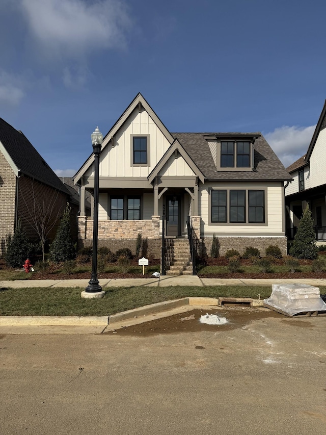 view of front of house with stone siding, board and batten siding, and a shingled roof