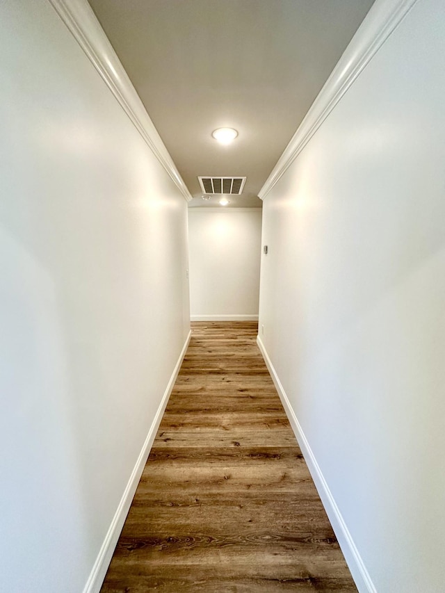 corridor featuring visible vents, crown molding, baseboards, and wood finished floors