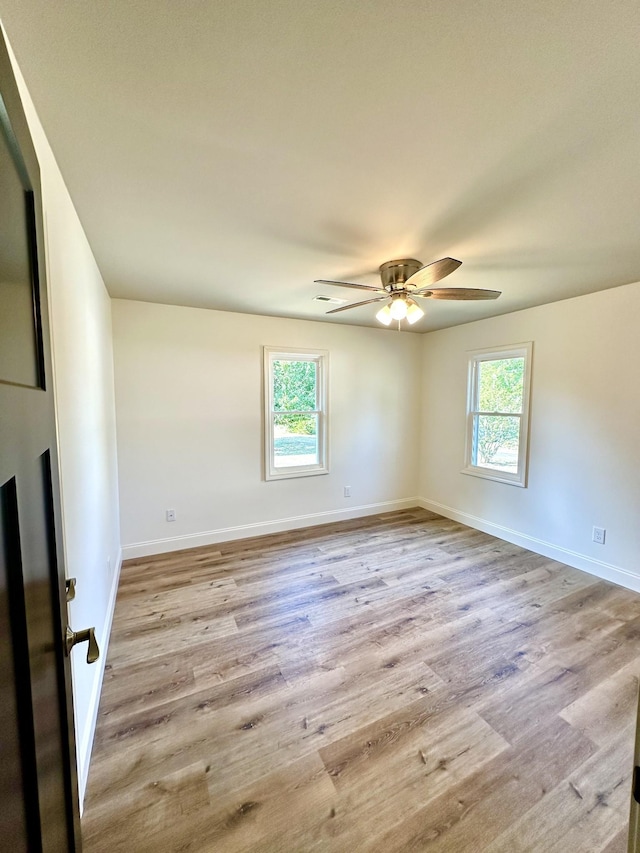 empty room featuring light wood finished floors, a ceiling fan, and baseboards