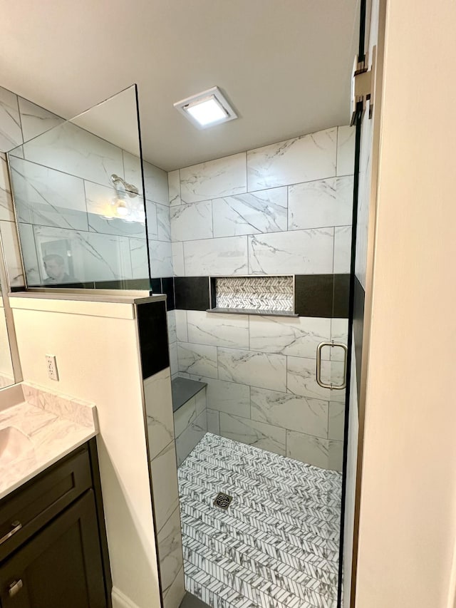 bathroom with a tile shower and vanity