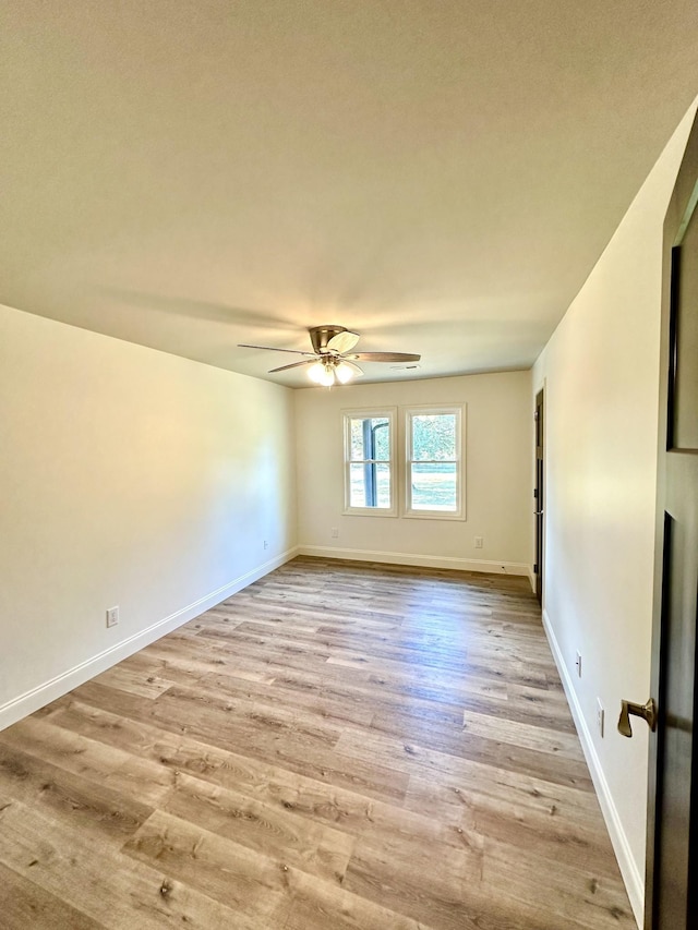 empty room with baseboards, ceiling fan, and light wood-style floors