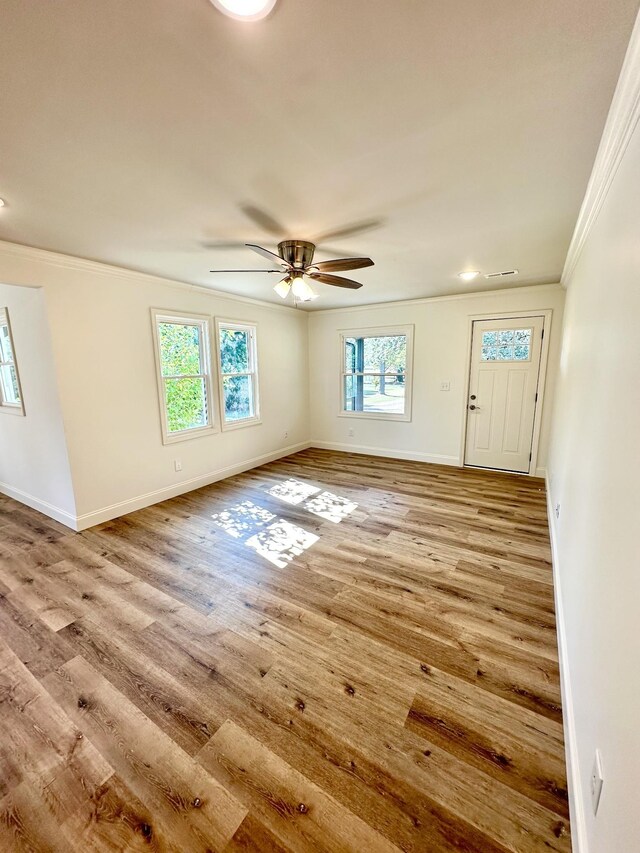 entrance foyer with crown molding, visible vents, ceiling fan, wood finished floors, and baseboards