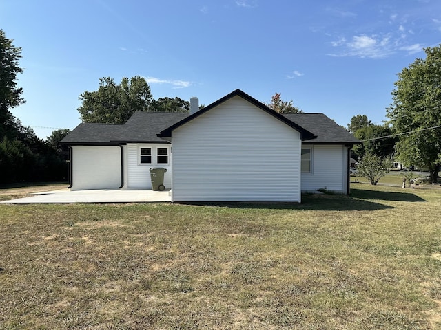 back of house featuring a yard, roof with shingles, and a patio