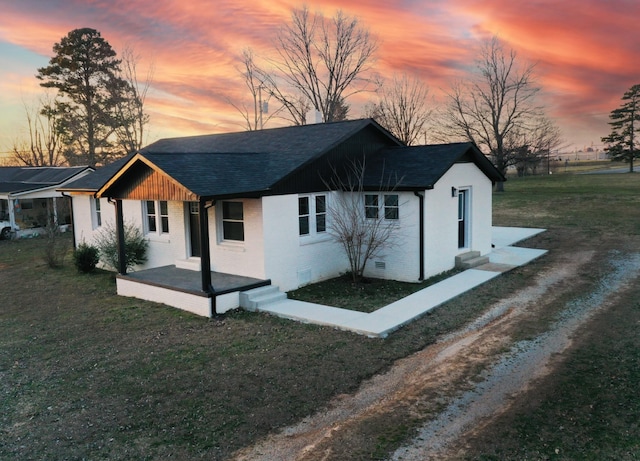 exterior space with a yard, brick siding, driveway, and roof with shingles