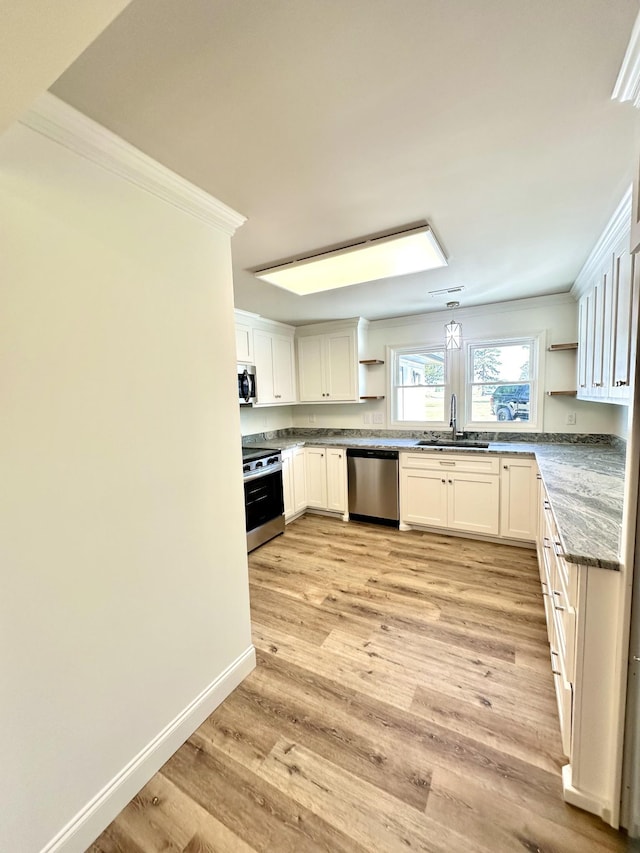 kitchen with a sink, light wood-style floors, appliances with stainless steel finishes, open shelves, and crown molding