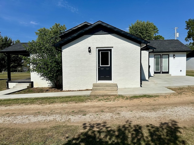 exterior space with entry steps, a patio, and brick siding