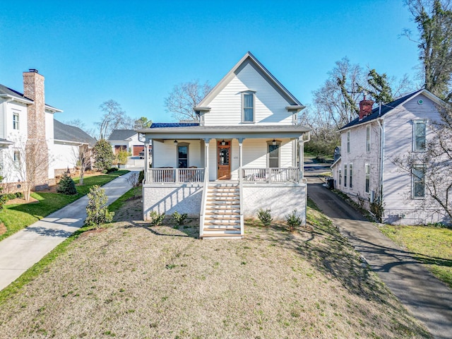 view of front of house featuring stairway, a porch, and a front yard