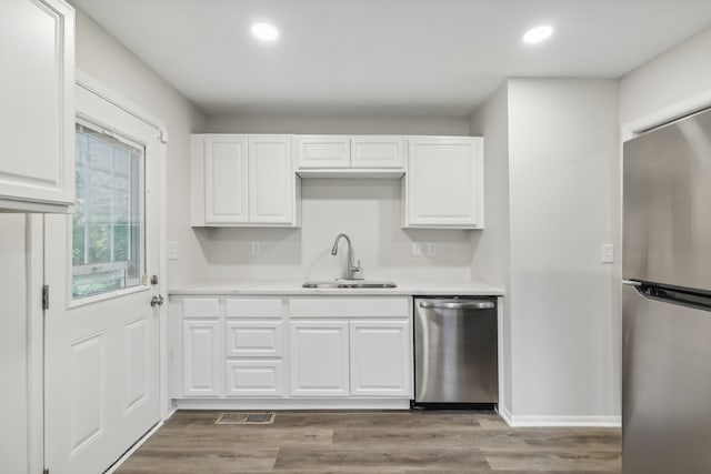 kitchen with stainless steel appliances, a sink, light countertops, and white cabinets