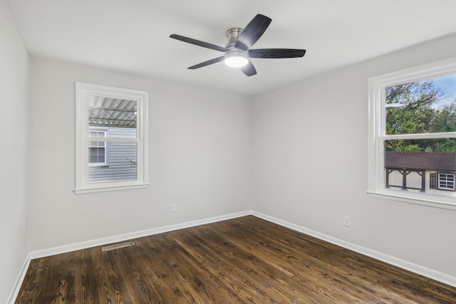 empty room with baseboards, visible vents, dark wood finished floors, and a ceiling fan