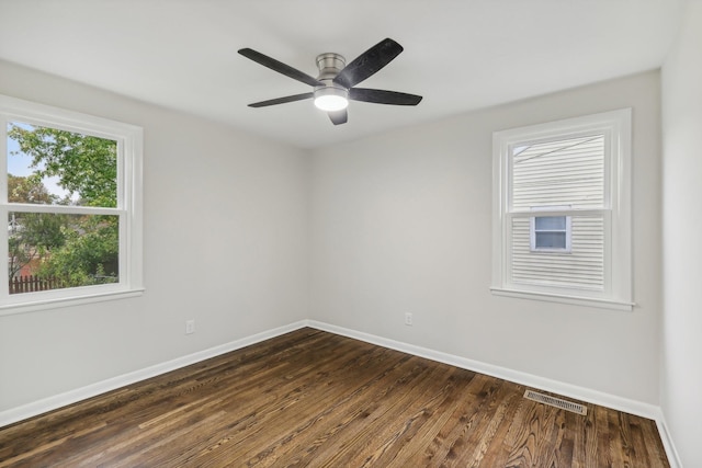 unfurnished room with dark wood-style floors, a ceiling fan, visible vents, and baseboards