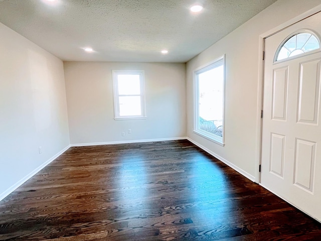 foyer entrance featuring a textured ceiling, dark wood-style flooring, and baseboards