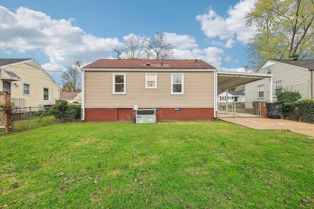 rear view of house featuring driveway, an attached carport, a lawn, and fence