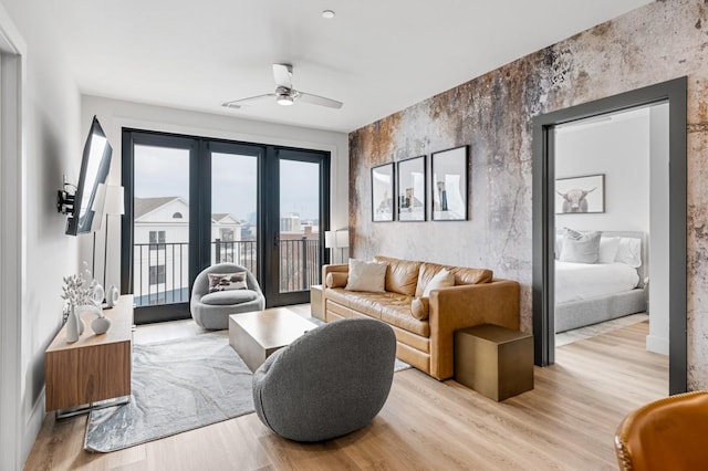 living room with light wood-type flooring, ceiling fan, and an accent wall