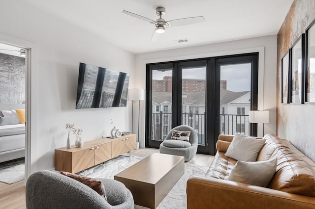 living room featuring plenty of natural light, light wood-style floors, visible vents, and ceiling fan