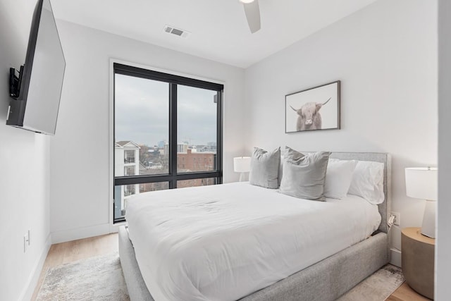 bedroom featuring visible vents, baseboards, wood finished floors, and a ceiling fan