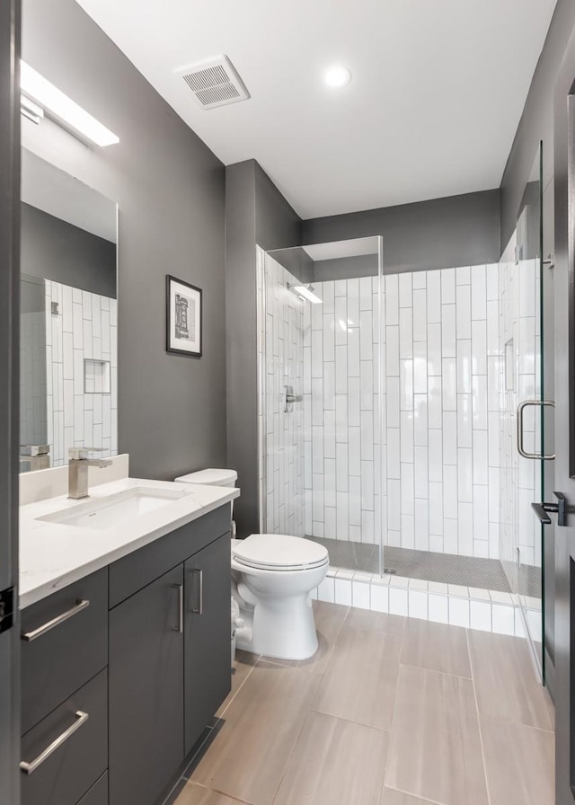 bathroom with visible vents, a stall shower, toilet, and vanity