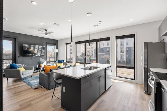 kitchen featuring stainless steel appliances, light wood finished floors, a kitchen bar, and a sink