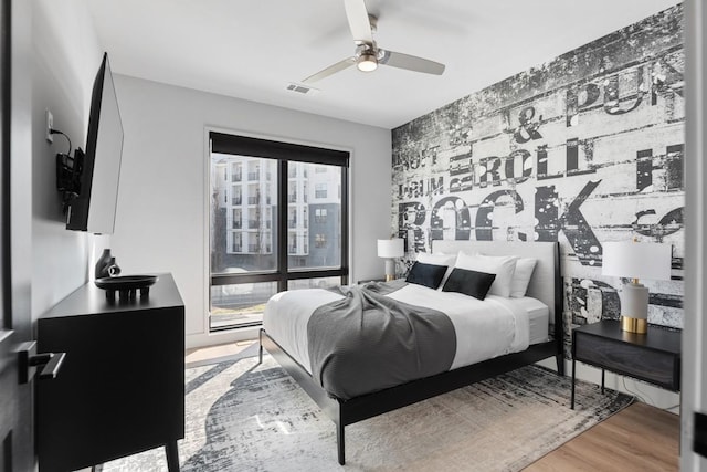 bedroom with ceiling fan, multiple windows, wood finished floors, and visible vents