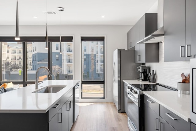 kitchen featuring appliances with stainless steel finishes, a wealth of natural light, a sink, and wall chimney range hood