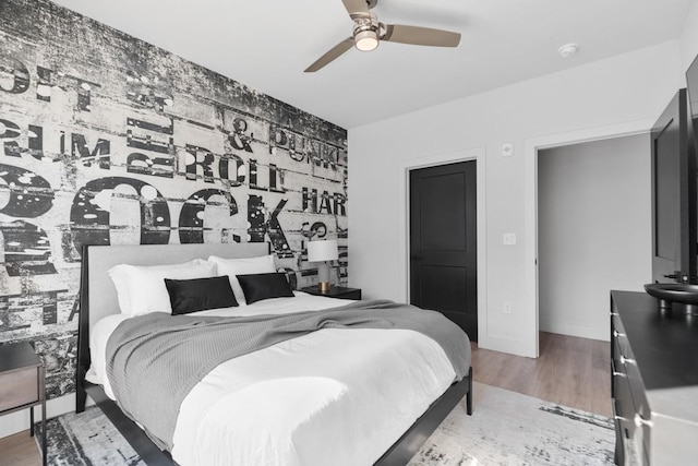 bedroom with ceiling fan, wood finished floors, and baseboards