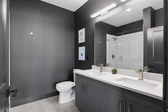 full bath featuring toilet, a stall shower, double vanity, and a sink