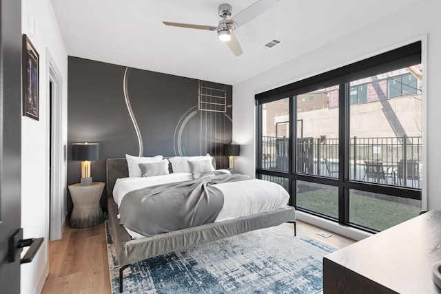 bedroom featuring light wood finished floors, visible vents, and a ceiling fan