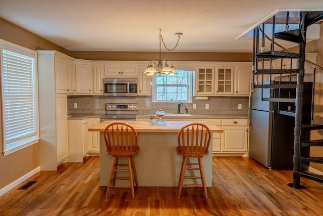 kitchen featuring tasteful backsplash, visible vents, appliances with stainless steel finishes, wood finished floors, and a center island