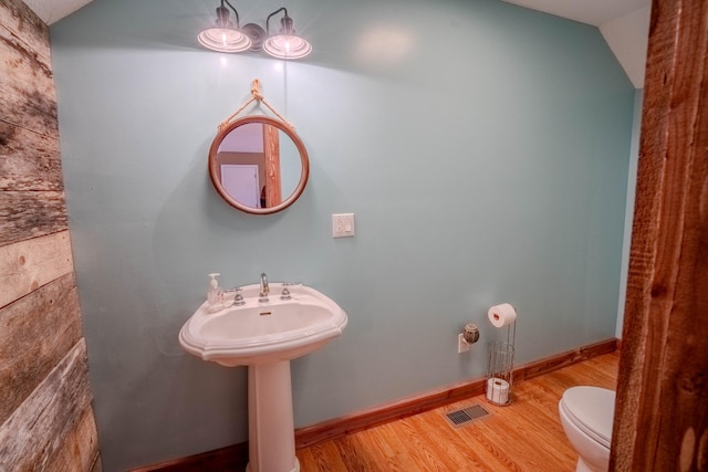 half bathroom featuring toilet, baseboards, visible vents, and wood finished floors