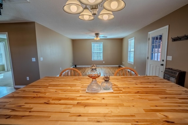 dining room with ceiling fan, a textured ceiling, wood finished floors, and heating unit