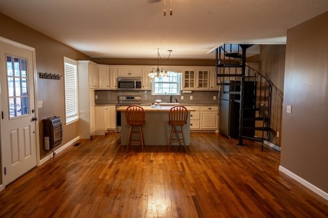 kitchen with appliances with stainless steel finishes, backsplash, a kitchen island, and heating unit