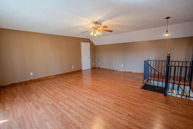 spare room with a ceiling fan, lofted ceiling, baseboards, and light wood finished floors