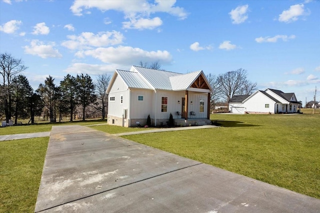 modern farmhouse featuring a front yard, metal roof, and driveway