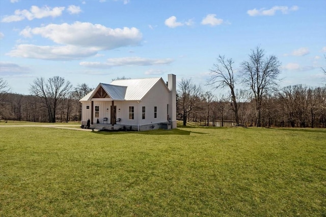 view of front of home featuring metal roof, a chimney, and a front yard