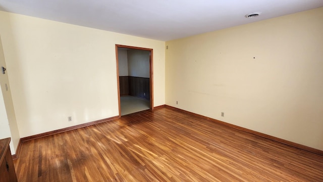 spare room featuring baseboards, visible vents, and wood finished floors