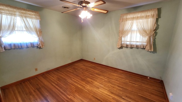 unfurnished room featuring visible vents, ceiling fan, baseboards, and wood finished floors