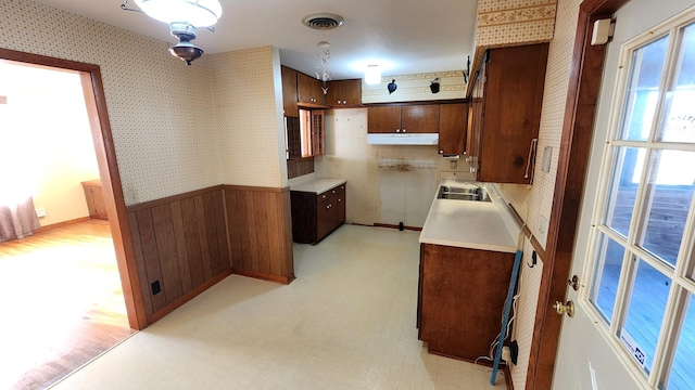 kitchen featuring wallpapered walls, visible vents, light floors, and a sink