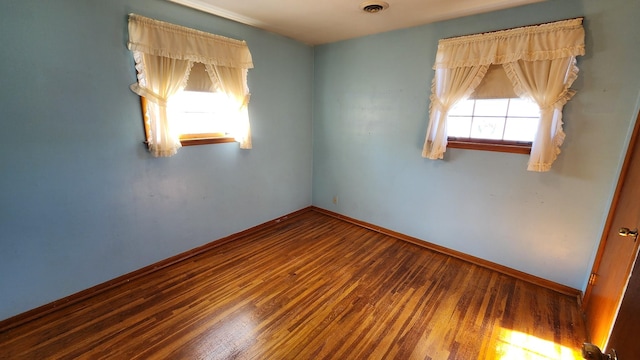 spare room with wood finished floors, visible vents, and baseboards