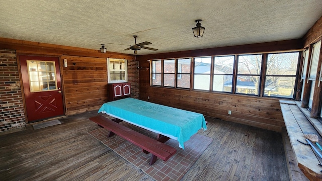 bedroom with a textured ceiling, hardwood / wood-style floors, and wood walls