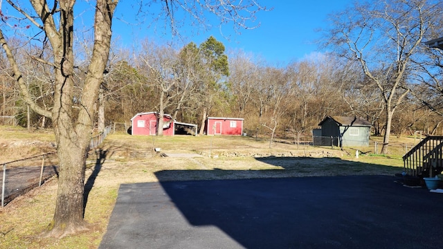 view of yard with an outbuilding, driveway, a shed, and fence