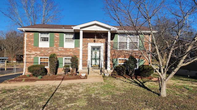 raised ranch with a front yard and brick siding