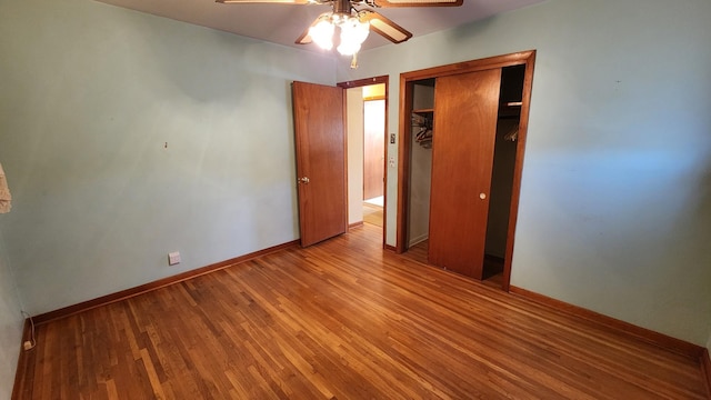 unfurnished bedroom featuring a closet, wood finished floors, a ceiling fan, and baseboards