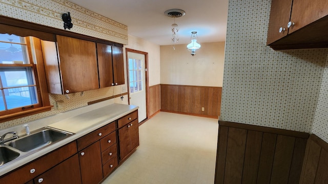 kitchen featuring wallpapered walls, visible vents, wainscoting, light countertops, and a sink