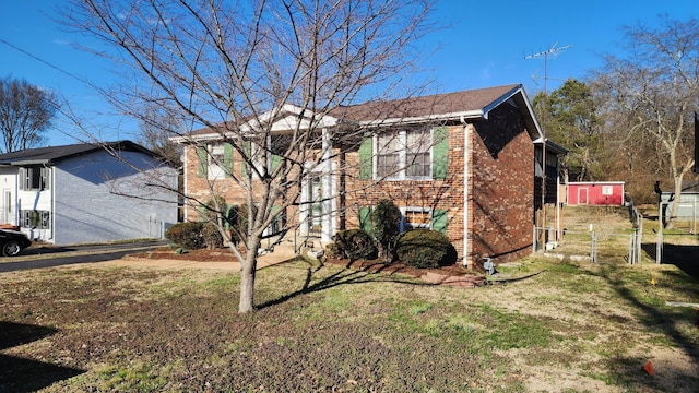 view of property exterior featuring a yard, fence, and brick siding