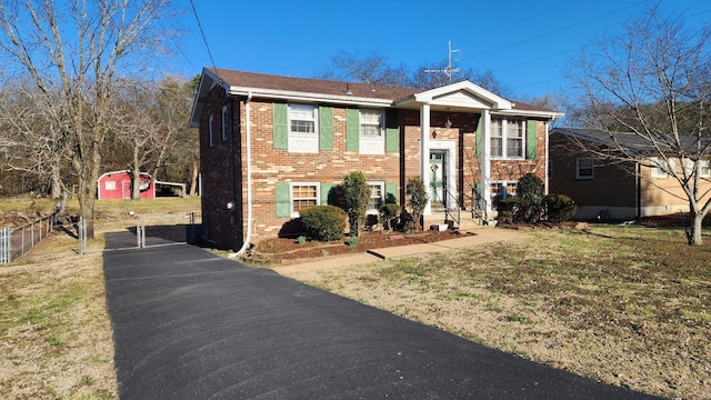 split foyer home with brick siding, a front yard, fence, and a gate