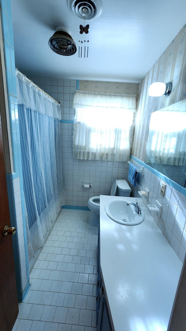 bathroom featuring toilet, a shower with shower curtain, tile walls, and vanity