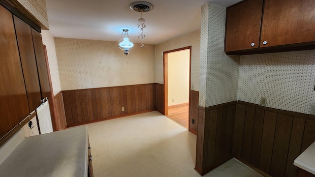 interior space featuring a wainscoted wall, wood walls, visible vents, and wallpapered walls