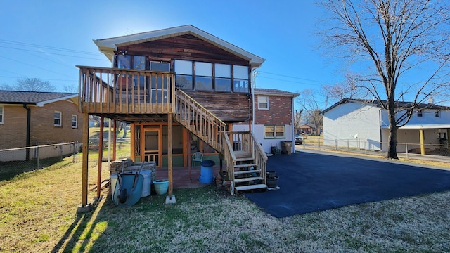 back of house featuring a sunroom, fence, stairway, and a lawn