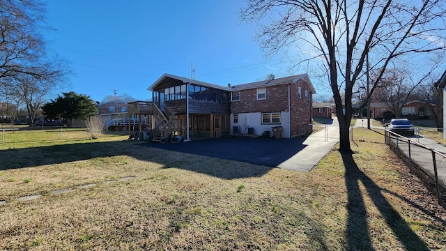 back of property with brick siding, fence, stairway, a lawn, and a patio area